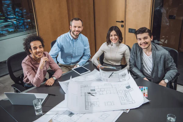 Group of successful architects sitting at conference hall at office and looking at camera — Stock Photo