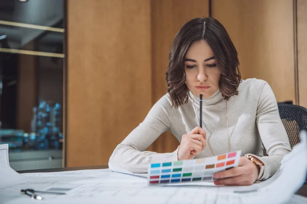 Nachdenkliche junge Designerin pflückt Farbe aus Palette — Stockfoto