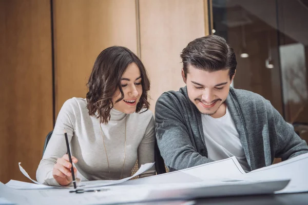 Happy young architects working with building plans together at office — Stock Photo