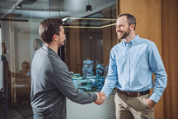 Glückliche Geschäftskollegen beim Händeschütteln im Büro — Stockfoto