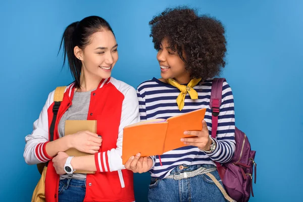 Cheerful multiethnic students posing with books, isolated on blue — Stock Photo