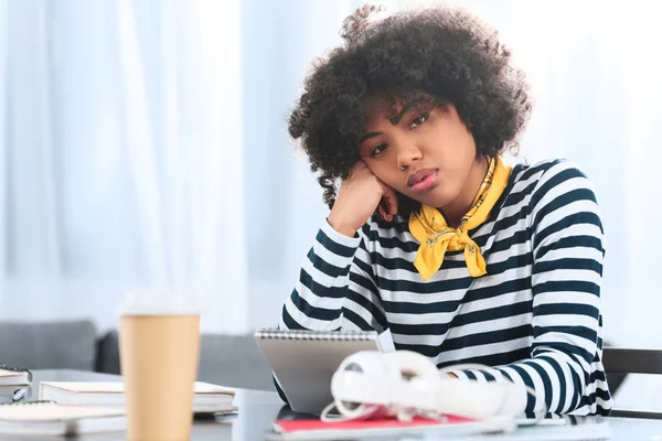 Retrato de estudante afro-americano entediado com caderno sentado à mesa — Fotografia de Stock