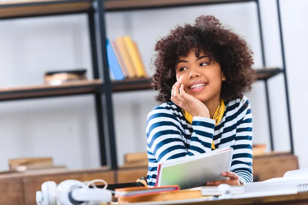 Ritratto di uno studente afroamericano sognante che distoglie lo sguardo mentre studia da solo — Foto stock