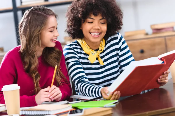 Portrait of young smiling multicultural students doing homework together — Stock Photo