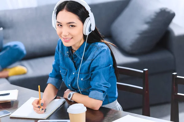 Retrato de sonriente asiático estudiante en auriculares mirando a cámara - foto de stock