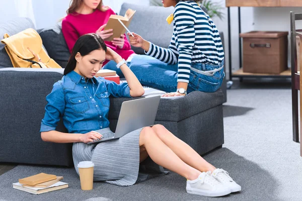 Asiático joven mujer usando laptop mientras haciendo tarea junto con multiétnicos amigos - foto de stock