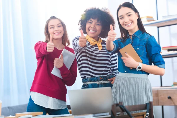 Retrato de estudiantes multiétnicos sonrientes mostrando pulgares hacia arriba - foto de stock