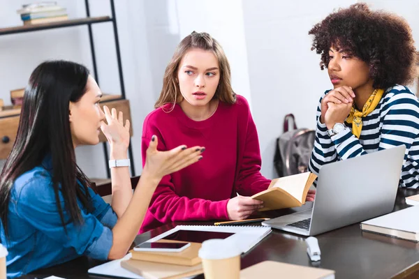 Multirassische Schüler diskutieren, während sie gemeinsam Hausaufgaben machen — Stockfoto