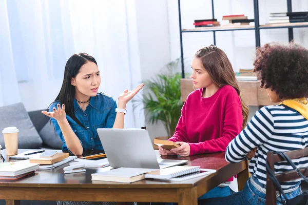 Multirassische Schüler diskutieren, während sie gemeinsam Hausaufgaben machen — Stockfoto