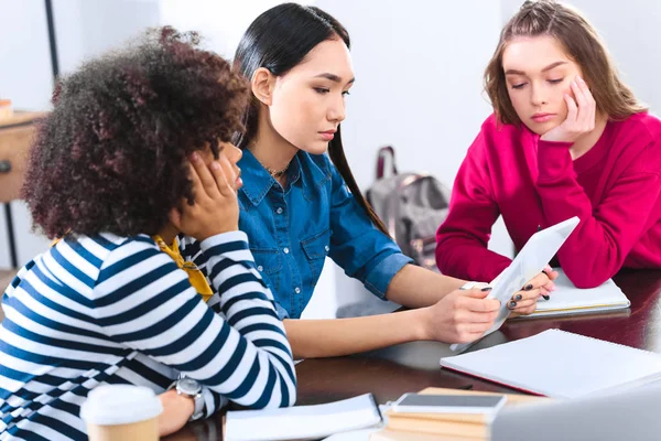 Estudiantes multiculturales enfocados usando tableta juntos - foto de stock