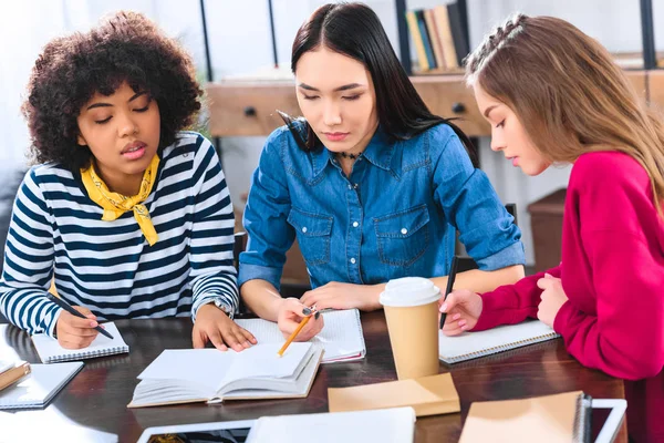 Retrato de estudiantes multirraciales enfocados haciendo tarea juntos - foto de stock