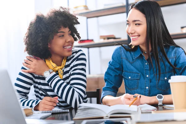 Retrato de estudiantes multirraciales alegres haciendo la tarea juntos - foto de stock