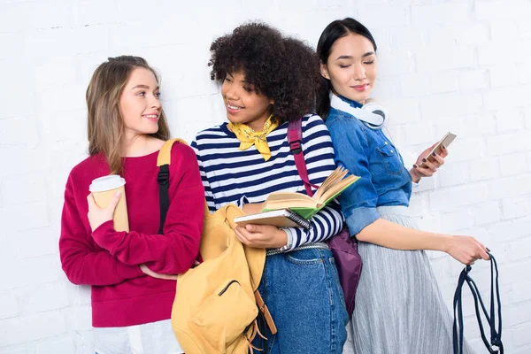 Portrait of young multiracial students standing against white brick wall — Stock Photo