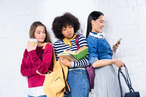 Retrato de jóvenes estudiantes multirraciales de pie contra la pared de ladrillo blanco - foto de stock