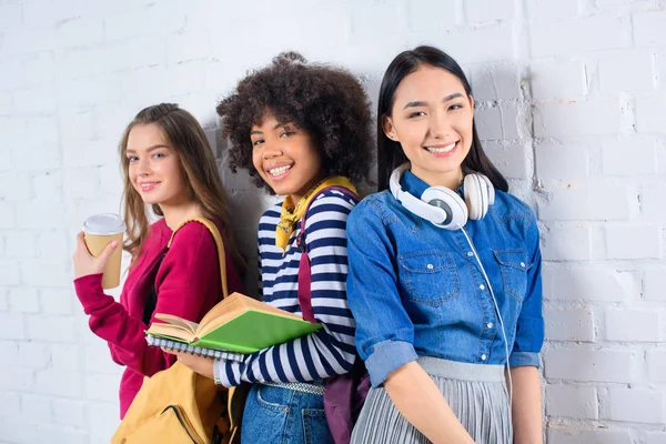 Retrato de jovens estudantes multirraciais em pé contra parede de tijolo branco — Fotografia de Stock