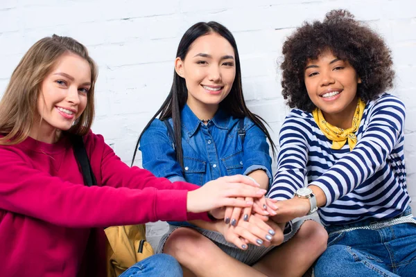 Retrato de estudiantes multiculturales sonrientes tomados de la mano - foto de stock