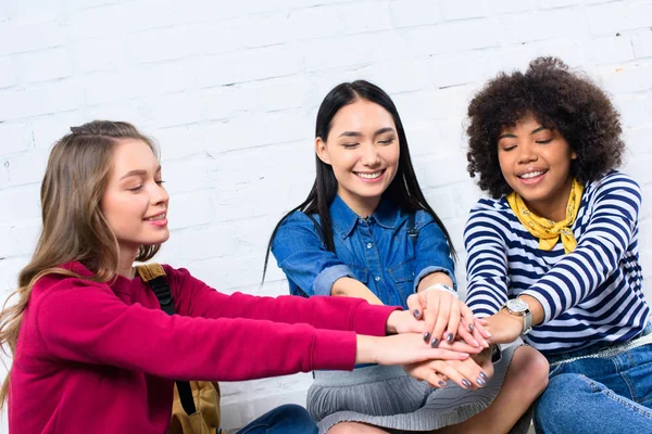 Retrato de estudiantes multiculturales sonrientes tomados de la mano - foto de stock