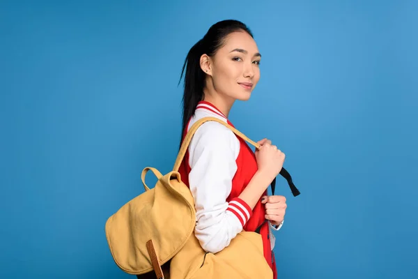 Side view of pretty asian student with backpack isolated on blue — Stock Photo