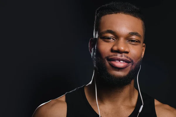 Bello giovane afro americano uomo in auricolare sorridente a fotocamera isolato su nero — Foto stock