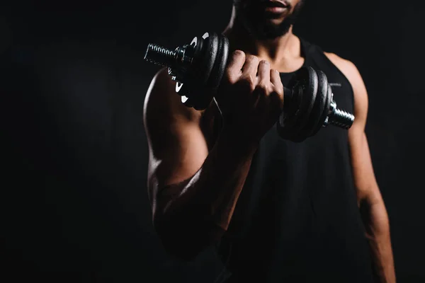 Corte tiro de muscular afro-americano homem exercitando com halteres isolado no preto — Fotografia de Stock