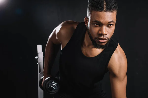 Bonito jovem afro-americano desportista exercitando com halteres no ginásio — Fotografia de Stock