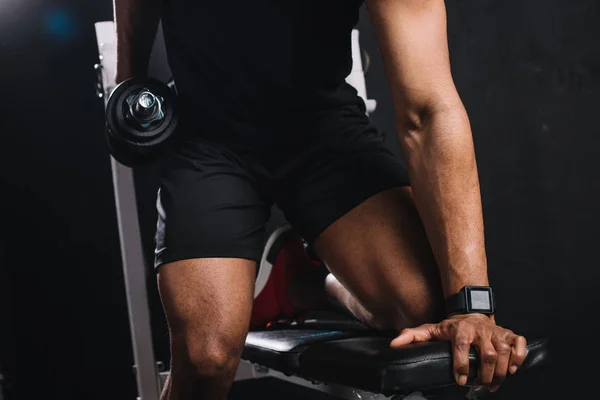 Cropped shot of muscular african american sportsman training with dumbbell in gym — Stock Photo