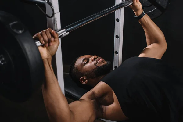 Musculoso joven afroamericano hombre en ropa deportiva elevación de la barra - foto de stock