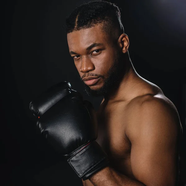 Ernster, hemdsloser afrikanisch-amerikanischer Boxer in Boxhandschuhen, der isoliert auf schwarz in die Kamera schaut — Stockfoto