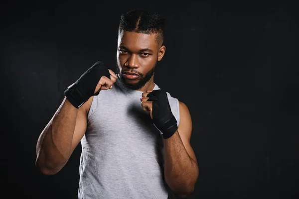 Serious young african american fighter looking at camera isolated on black — Stock Photo