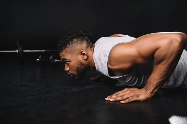 Visão lateral do jovem homem americano africano muscular fazendo flexões e olhando para longe — Fotografia de Stock