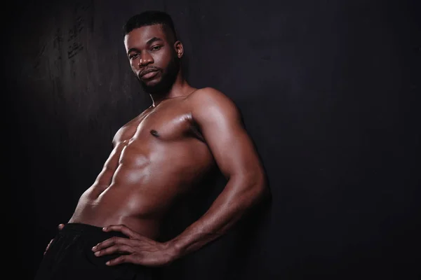 Красивий без сорочки м'язистий афроамериканський чоловік дивиться на камеру на чорному — стокове фото