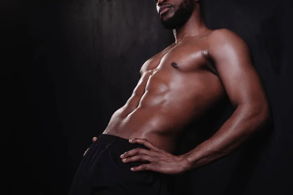 Schnappschuss eines muskulösen, hemdlosen Mannes, der mit den Händen auf der Taille auf schwarz steht — Stockfoto