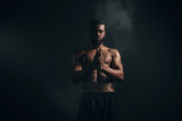 Joven afroamericano deportista aplicando talco en polvo y mirando a la cámara en negro - foto de stock