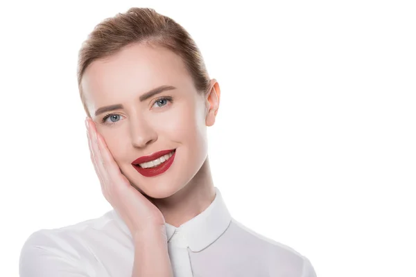 Mulher sorridente com maquiagem tocando próprio rosto isolado no branco — Fotografia de Stock