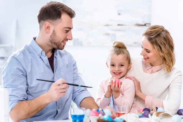 Bambino che tiene l'uovo di Pasqua sorridendo ai genitori — Foto stock