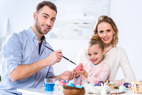 Father and daughter smiling while painting Easter eggs — Stock Photo