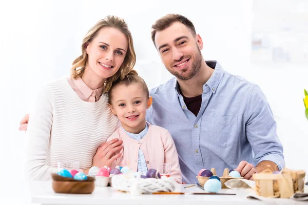 Cheerful family smiling by painted eggs for Easter — Stock Photo