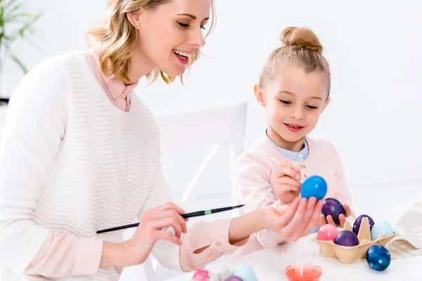 Mother helping daughter to color Easter eggs — Stock Photo