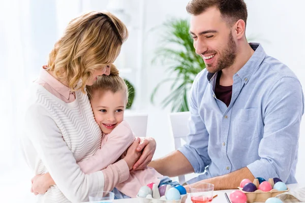 Cheerful family embracing by painted eggs for Easter — Stock Photo