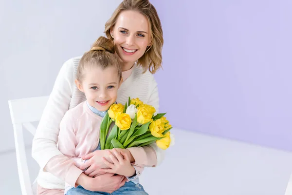 Abrazando a madre e hija sosteniendo tulipanes para el día de la mujer - foto de stock