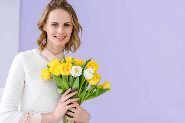 Femme blonde souriante tenant un bouquet de tulipes pour 8 mars — Photo de stock