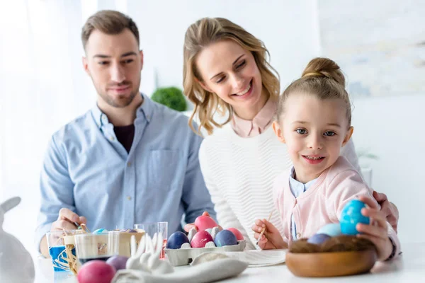 Feiernde Familie arrangiert bemalte Eier im Nest zur Osterdekoration — Stock Photo