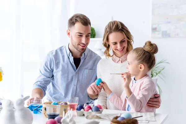 Родители и дочь рисуют пасхальные яйца — стоковое фото
