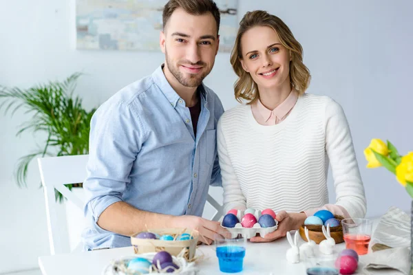 Happy young man and woman coloring Easter eggs — Stock Photo