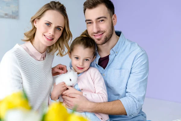 Happy family holding white rabbit — Stock Photo