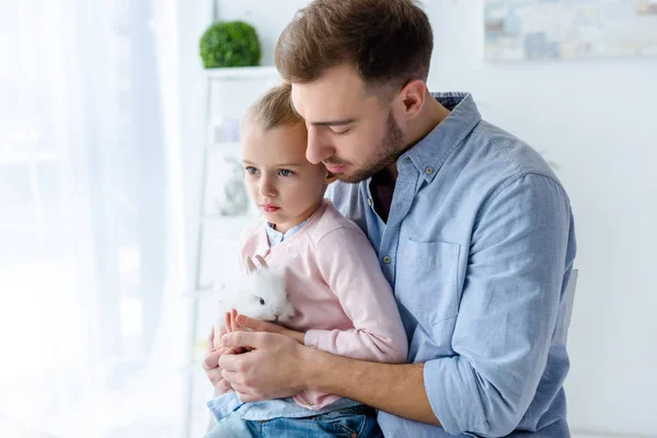 Father and daughter cuddling white rabbit — Stock Photo