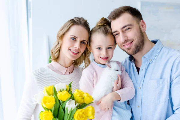 Smiling family with cute bunny looking at camera — Stock Photo