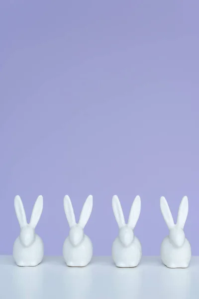 Bunny statuettes in row on violet background — Stock Photo