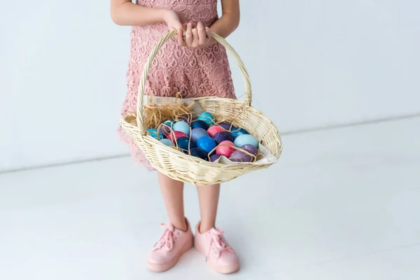 Child holding basket with colored Easter eggs — Stock Photo