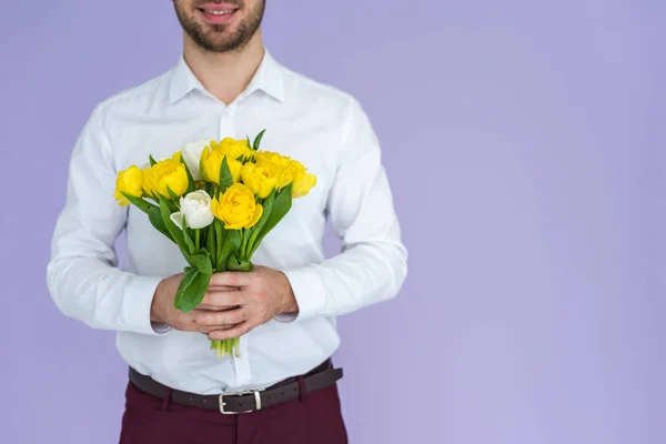 Человек держит букет тюльпанов изолирован на фиолетовый — стоковое фото